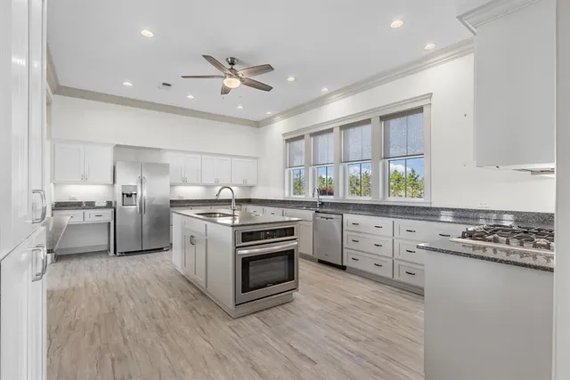 a kitchen with white cabinets stainless steel appliances and window