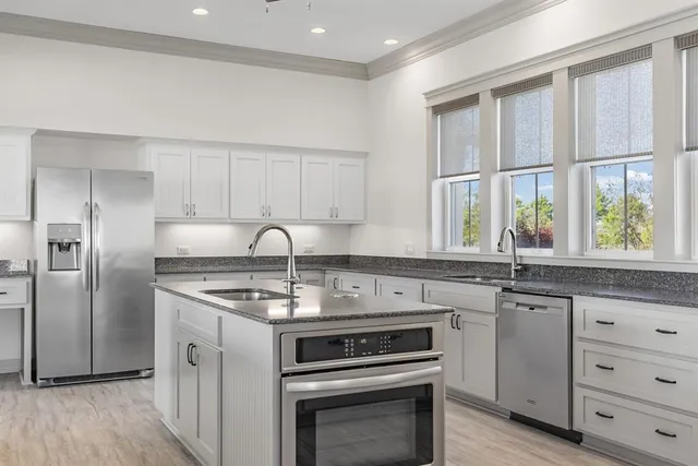 a kitchen with white cabinets stainless steel appliances and a window