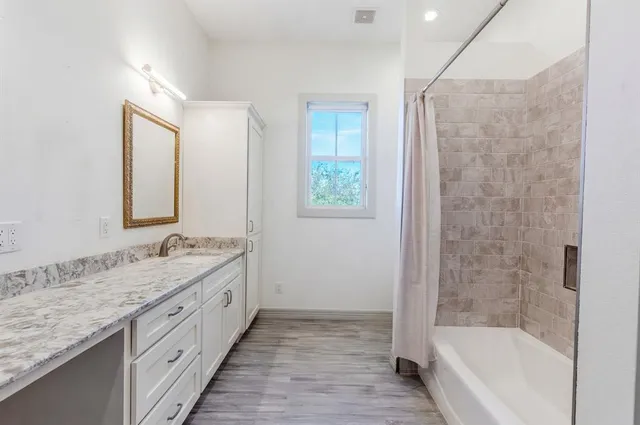 a bathroom with a granite countertop bathtub shower sink and mirror