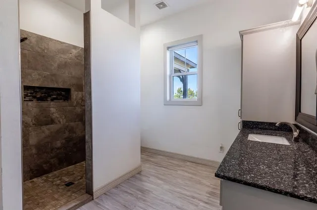 a bathroom with a granite countertop shower a mirror and a sink