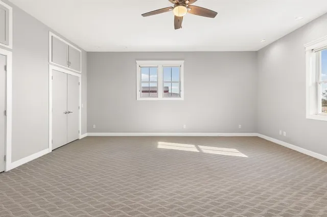 an empty room with a window and a fan