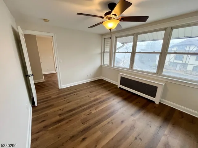 a view of an empty room with window and wooden floor