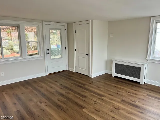 an empty room with wooden floor fireplace and windows
