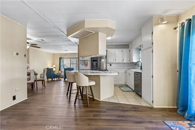 a living room with stainless steel appliances furniture a dining table and chairs with wooden floor