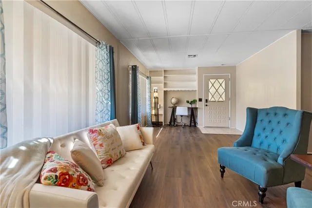 a living room with stainless steel appliances furniture a dining table and chairs with wooden floor