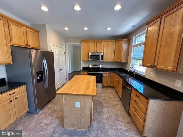 a kitchen with stainless steel appliances granite countertop a refrigerator a stove and a sink