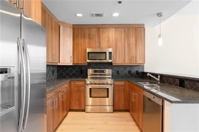 a kitchen with stainless steel appliances granite countertop a stove a refrigerator and a sink
