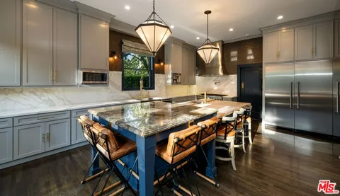 a kitchen with granite countertop kitchen island stainless steel appliances a dining table and chairs