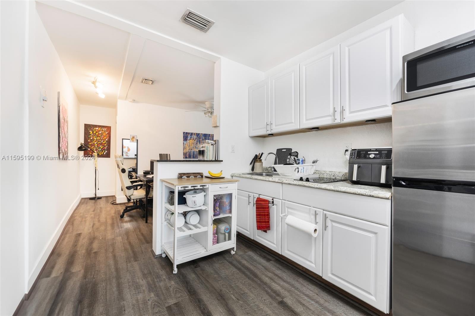 4420 Northwest 3rd Avenue Miami, FL 33127 - Photo 15 of 36 a kitchen with stainless steel appliances granite countertop a stove top oven a sink dishwasher and white cabinets with wooden floor
