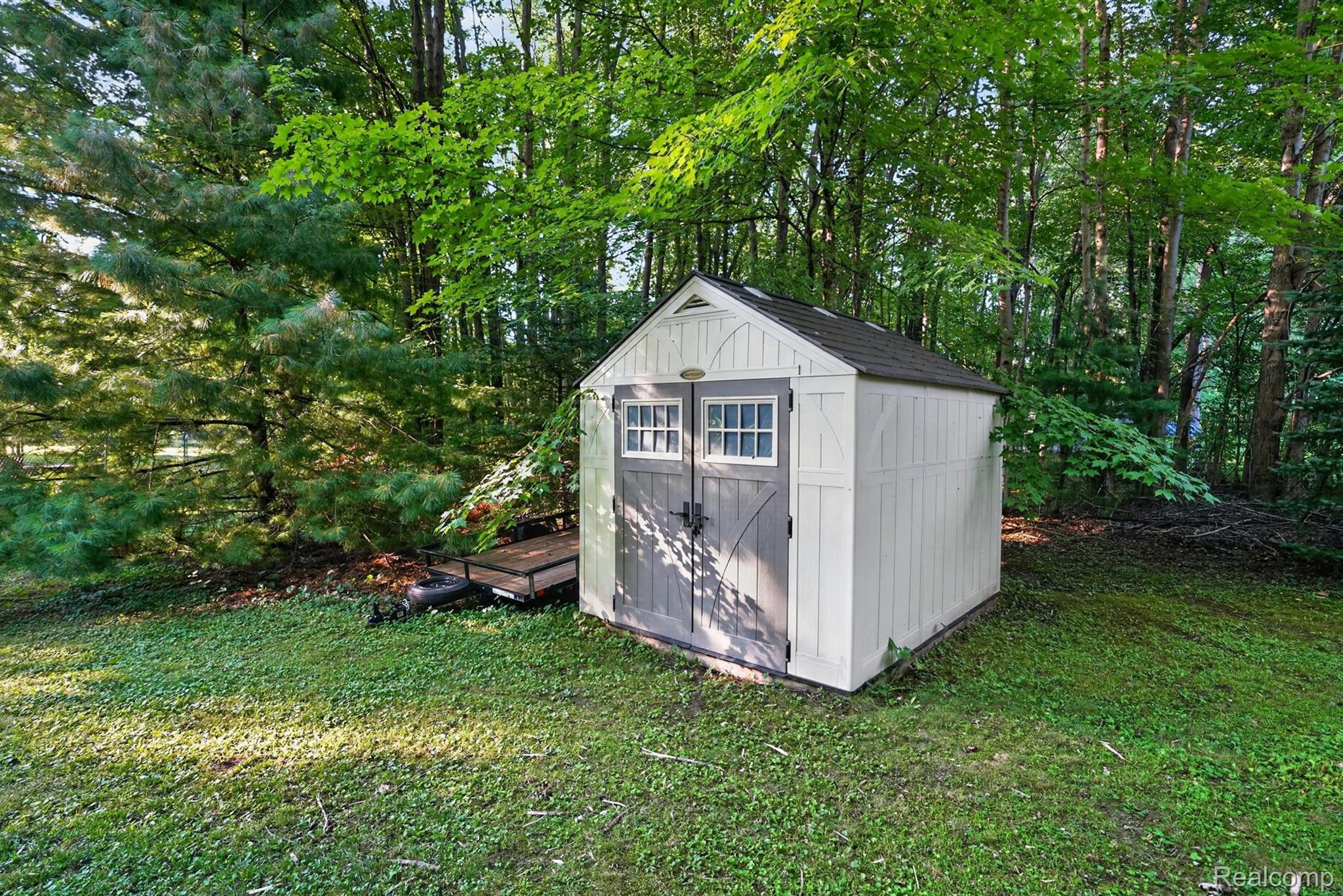 8696 West Sargent Road Fowlerville, MI 48836 - Photo 33 of 36 Detached storage shed featuring double doors with window panes, a pitched roof, and a light-colored siding finish