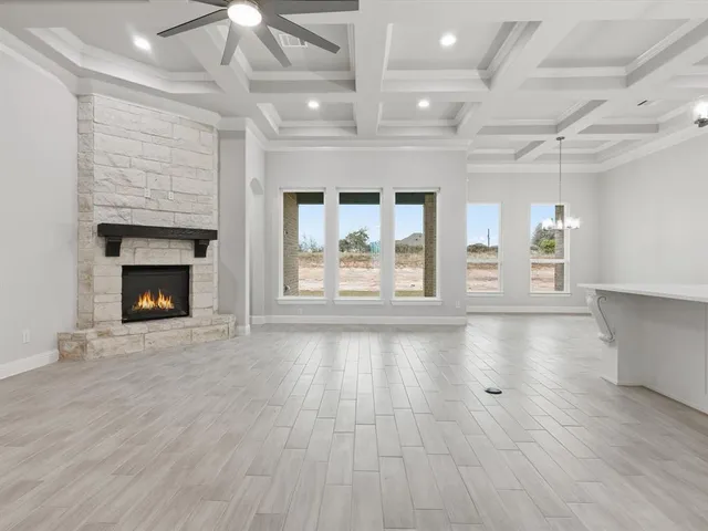 an empty room with wooden floor fireplace cabinet and windows