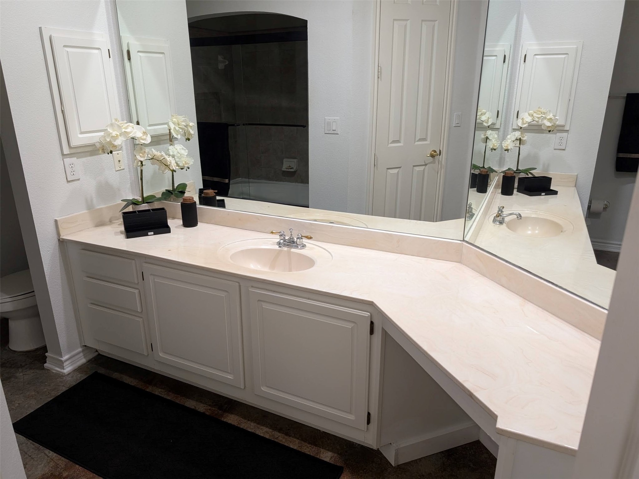 2400 McCue Road, Unit 136 Houston, TX 77056 - Photo 12 of 25 Spacious bathroom with a large corner vanity featuring dual sinks and ample storage. The neutral color palette and mirrored walls enhance the light and openness.