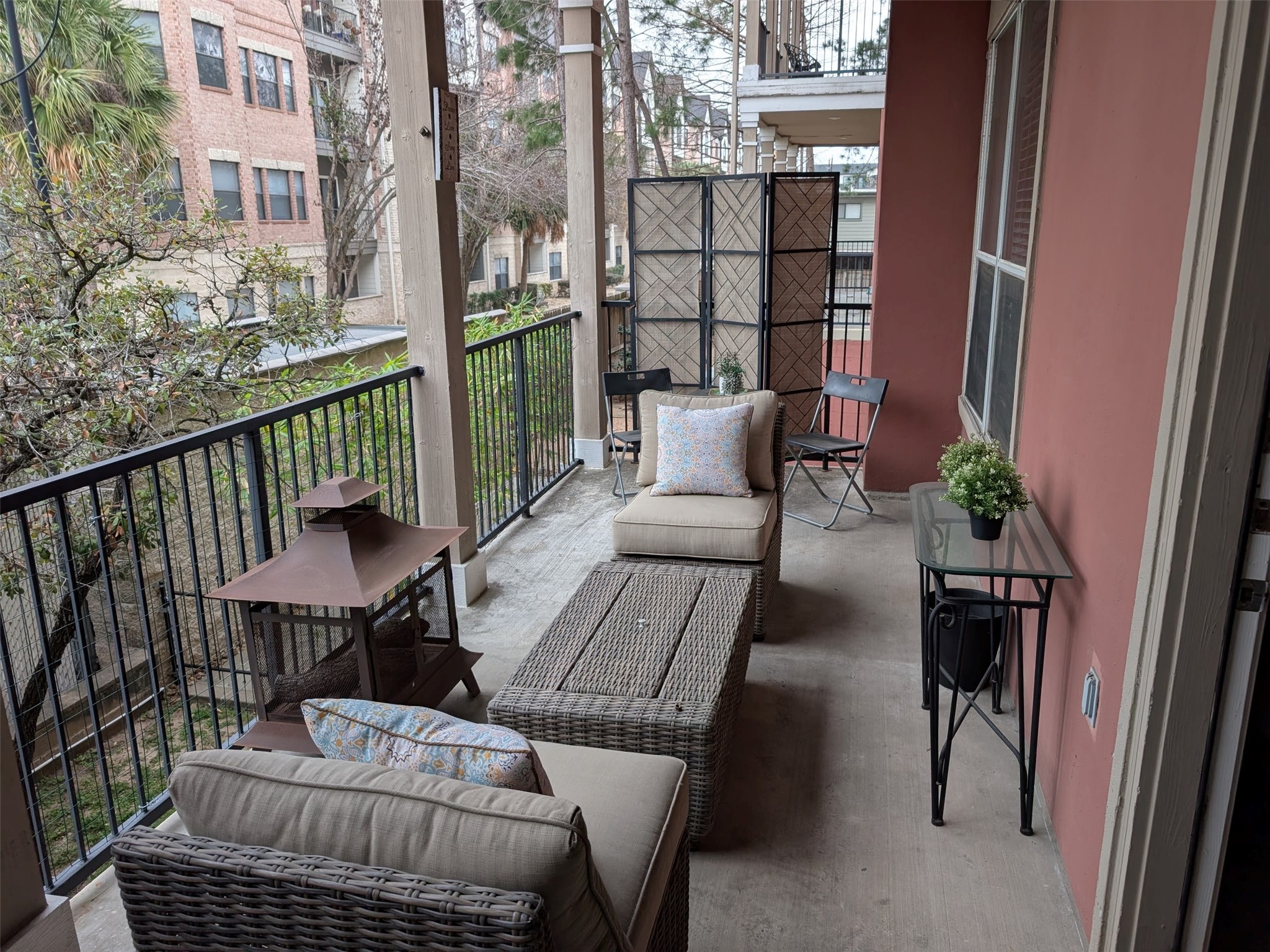 2400 McCue Road, Unit 136 Houston, TX 77056 - Photo 15 of 25 This photo showcases a cozy balcony with comfortable seating, a small table, and decorative plants. It's perfect for relaxing outdoors, with views of surrounding buildings and greenery. Ideal for enjoying fresh air and a quiet retreat.