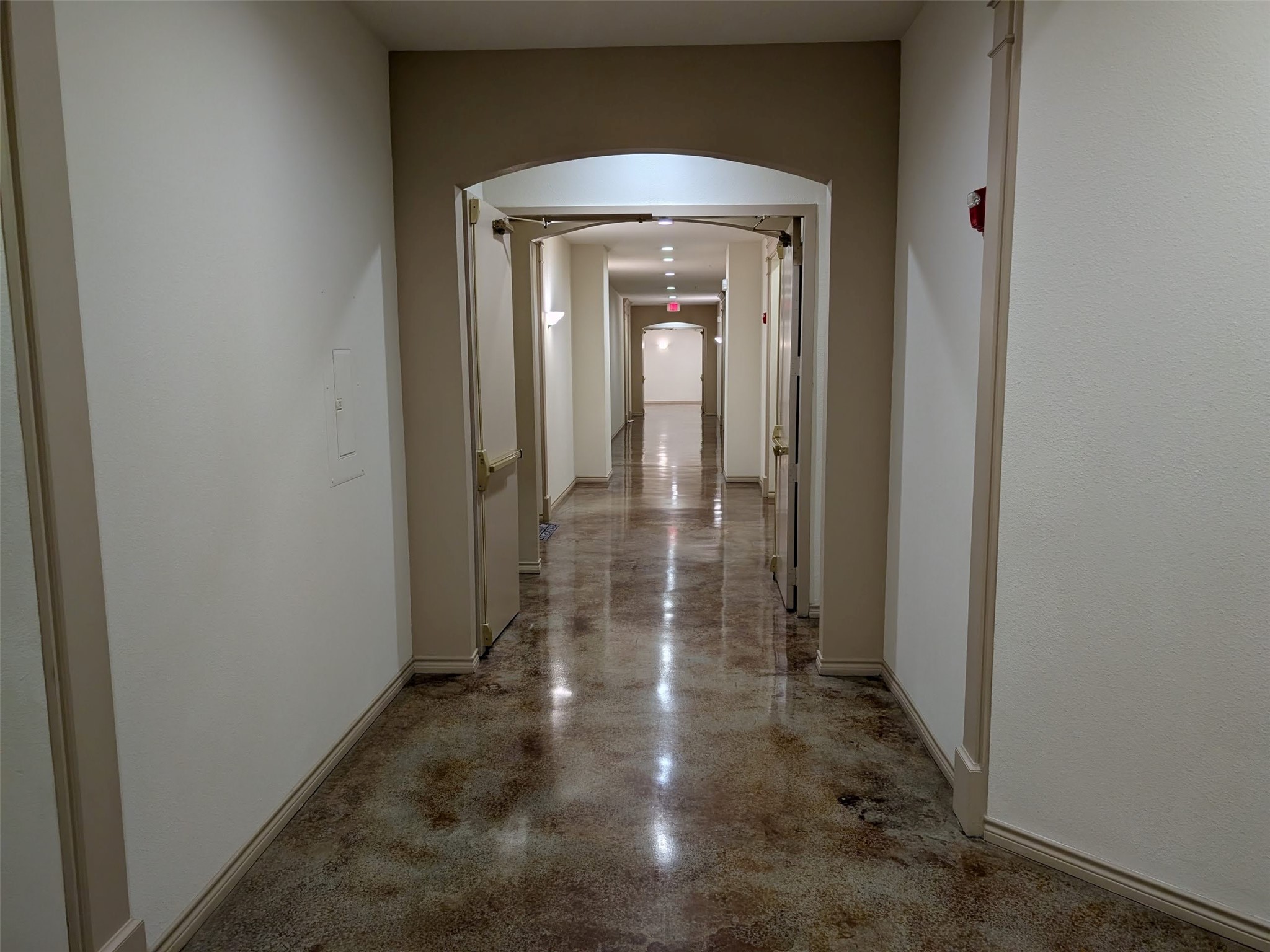 2400 McCue Road, Unit 136 Houston, TX 77056 - Photo 17 of 25 This photo shows a clean, well-lit hallway with polished floors and neutral-colored walls, leading to various doorways. Ideal for a residential setting with a modern, minimalistic design.