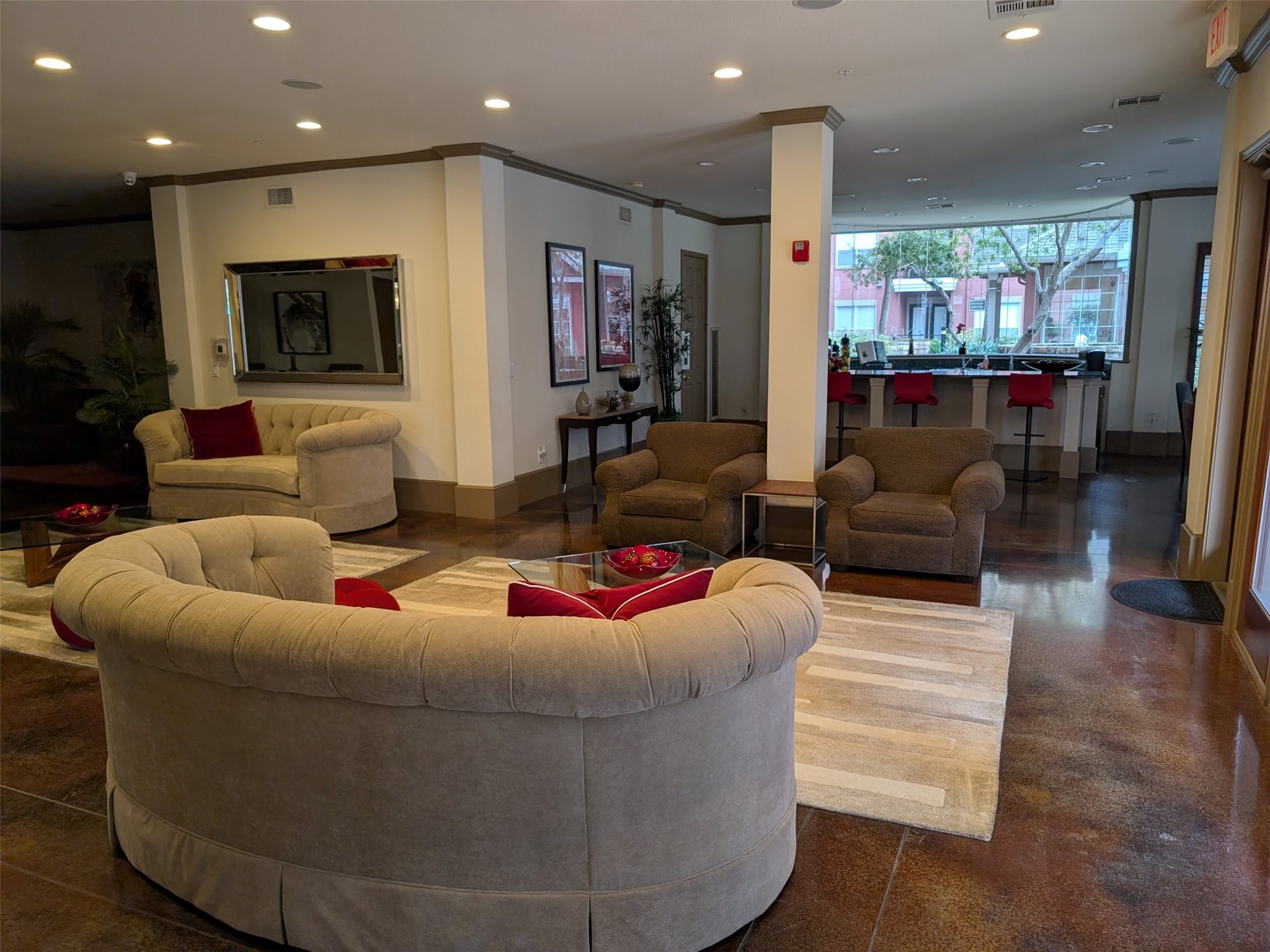 2400 McCue Road, Unit 136 Houston, TX 77056 - Photo 21 of 25 This photo showcases a spacious, modern living area with plush seating, warm lighting, and stylish decor. It features large windows that let in natural light, a sleek bar area with red stools, and elegant accents throughout, creating a welcoming and comfortable space.