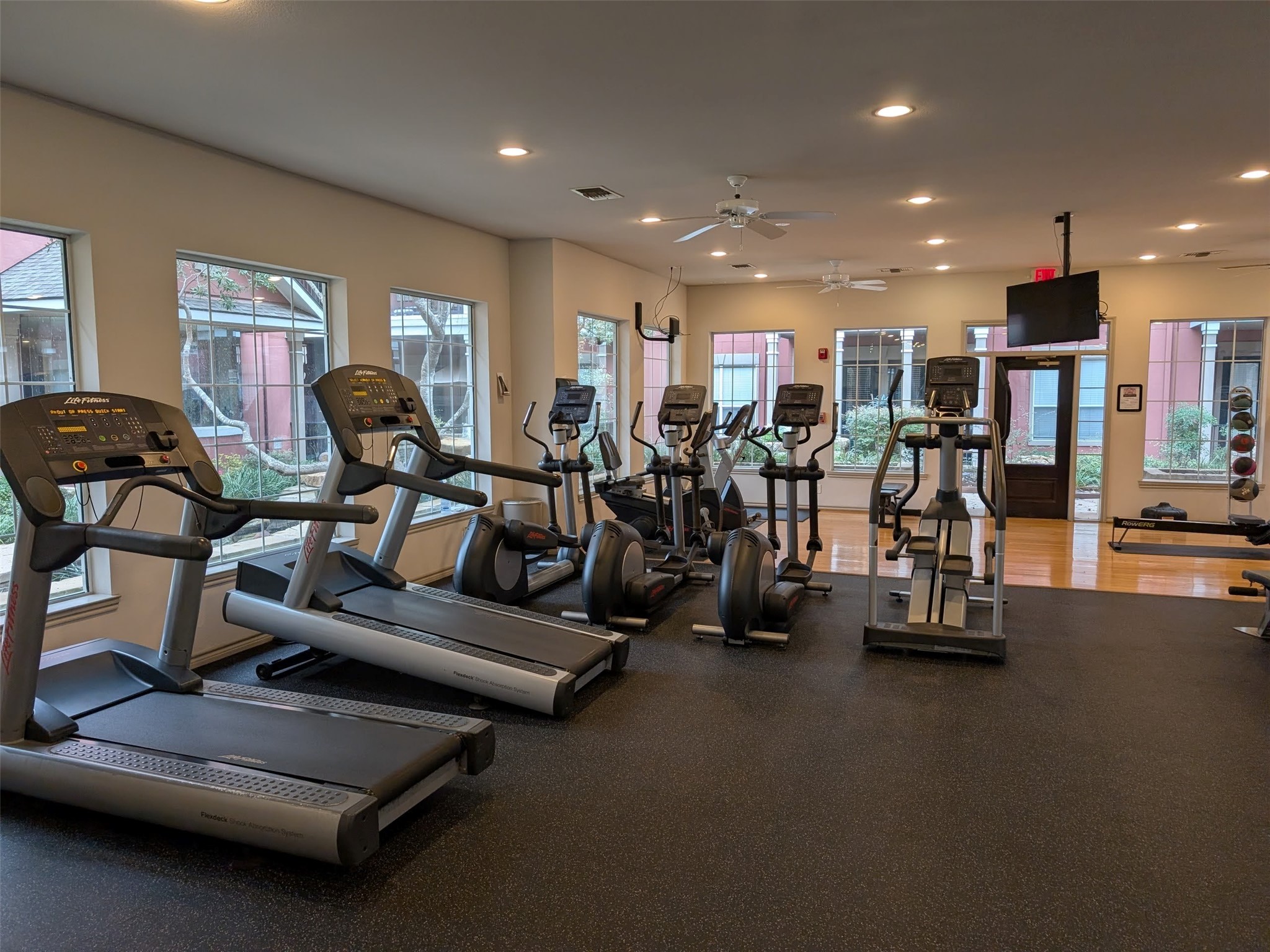 2400 McCue Road, Unit 136 Houston, TX 77056 - Photo 25 of 25 This photo shows a well-equipped gym with several treadmills, elliptical machines, and a set of free weights. The room is spacious and well-lit with large windows, offering a comfortable workout environment.