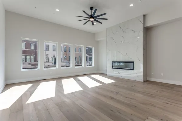 a view of an empty room with window and wooden floor