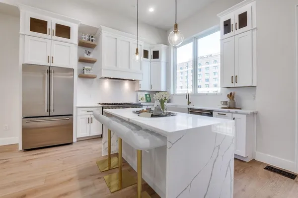 a kitchen with kitchen island a sink a stove a refrigerator and white cabinets