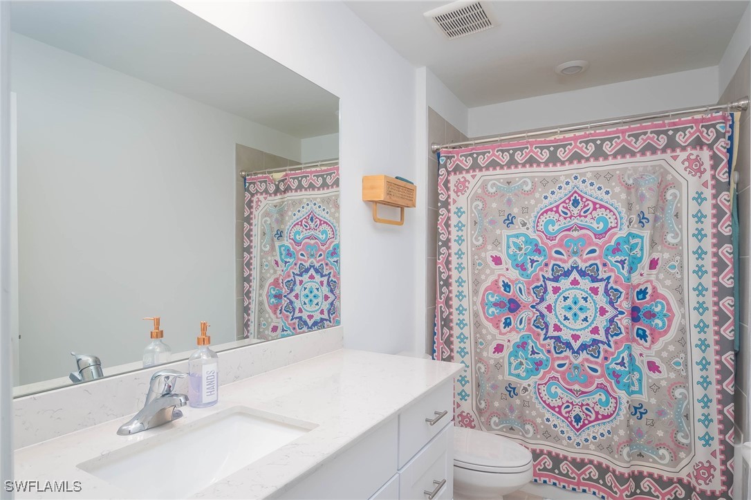 12310 Dakota Ridge Place Lehigh Acres, FL 33974 - Photo 26 of 34 a bathroom with a sink a toilet and shower curtain