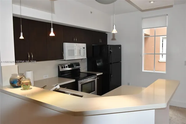 a kitchen with stainless steel appliances kitchen island granite countertop a refrigerator a sink and blue cabinets