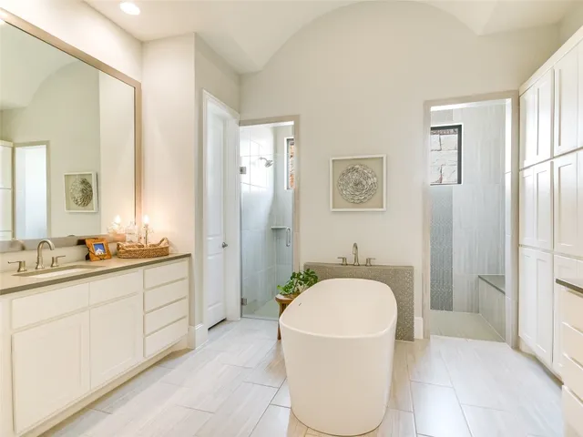 a spacious bathroom with a tub sink and mirror