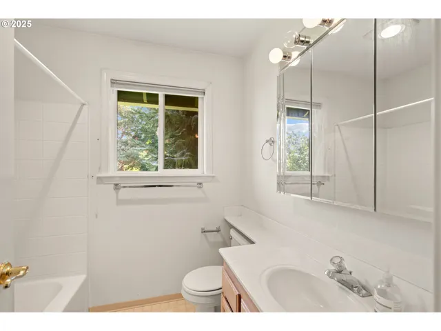 a bathroom with a sink a toilet a window and shower