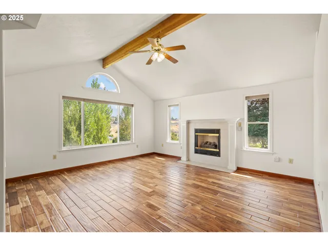 an empty room with wooden floor fireplace and windows