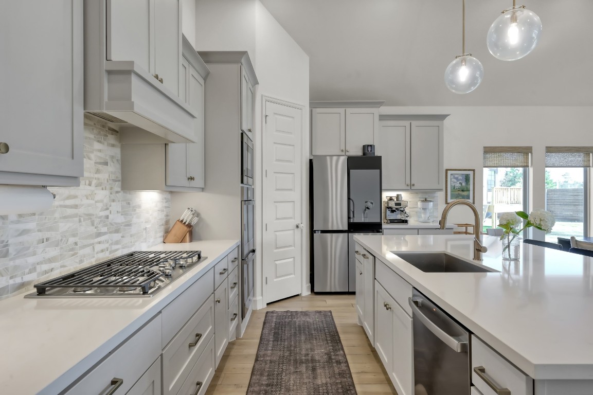 17801 Parnassum Path Conroe, TX 77302 - Photo 9 of 32 Quartz countertops, a stylish tile backsplash, and brass finishes set the tone for this refined, modern kitchen.