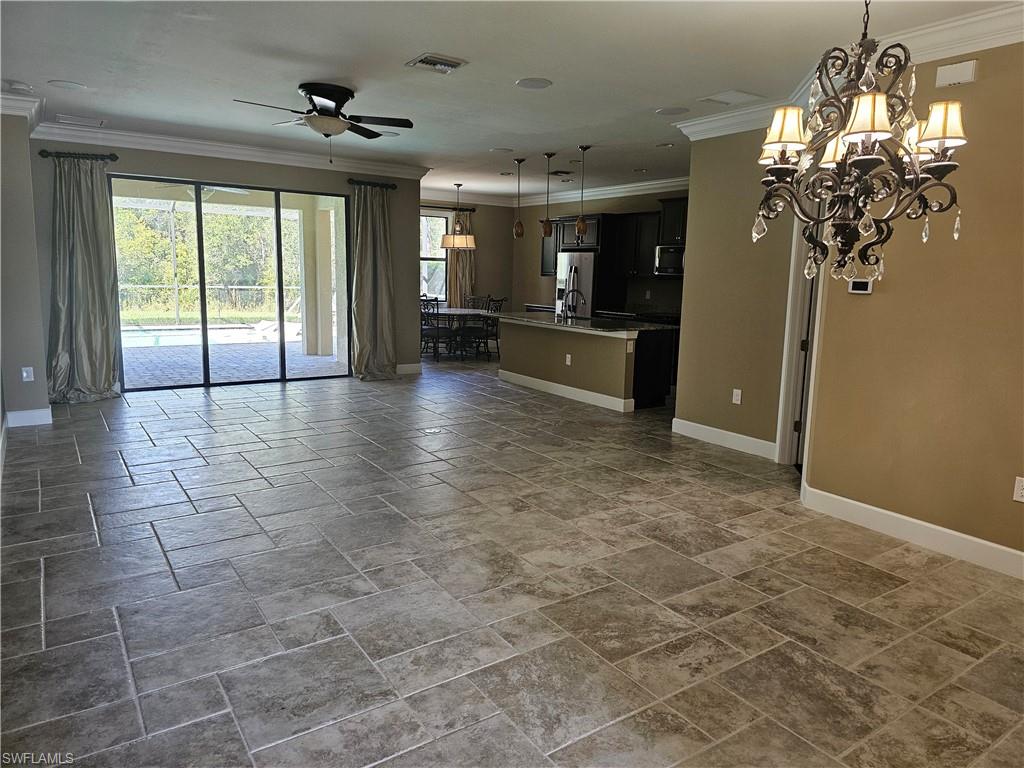10840 Rutherford Road Fort Myers, FL 33913 - Photo 4 of 35 Unfurnished living room featuring tile patterned floors, ornamental molding, ceiling fan with notable chandelier, and a wealth of natural light