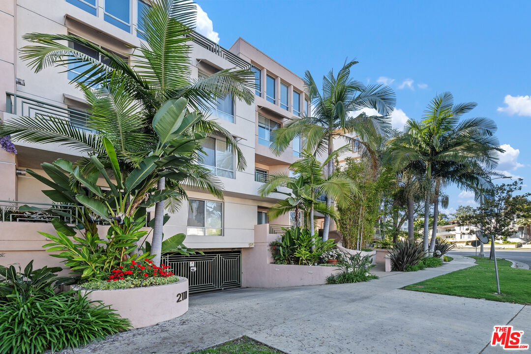 a front view of multi story residential apartment building with yard and potted plants