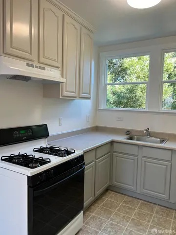 a kitchen with granite countertop stainless steel appliances a stove a sink and a window