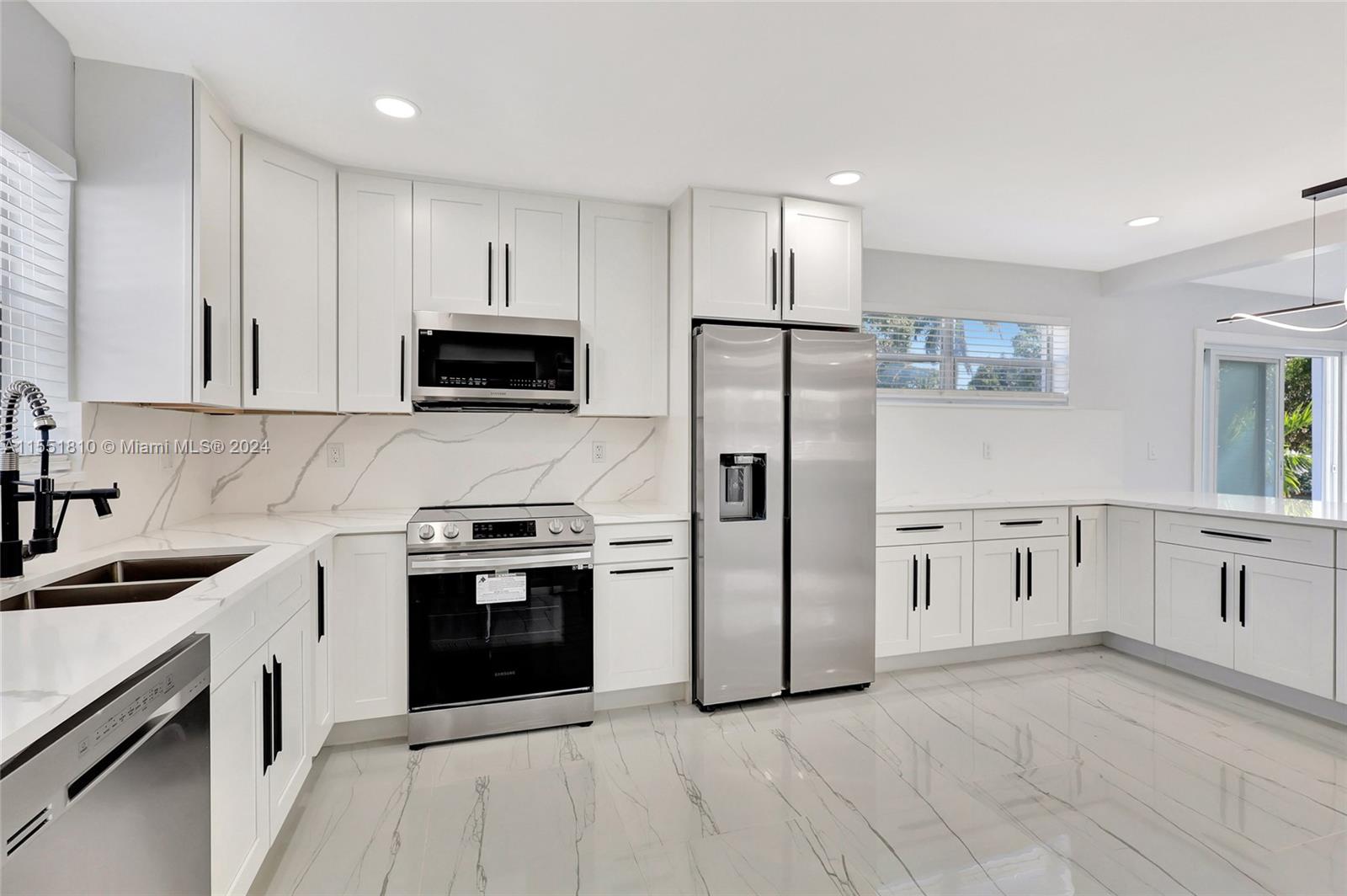 a kitchen with stainless steel appliances granite countertop a stove top oven a refrigerator and white cabinets