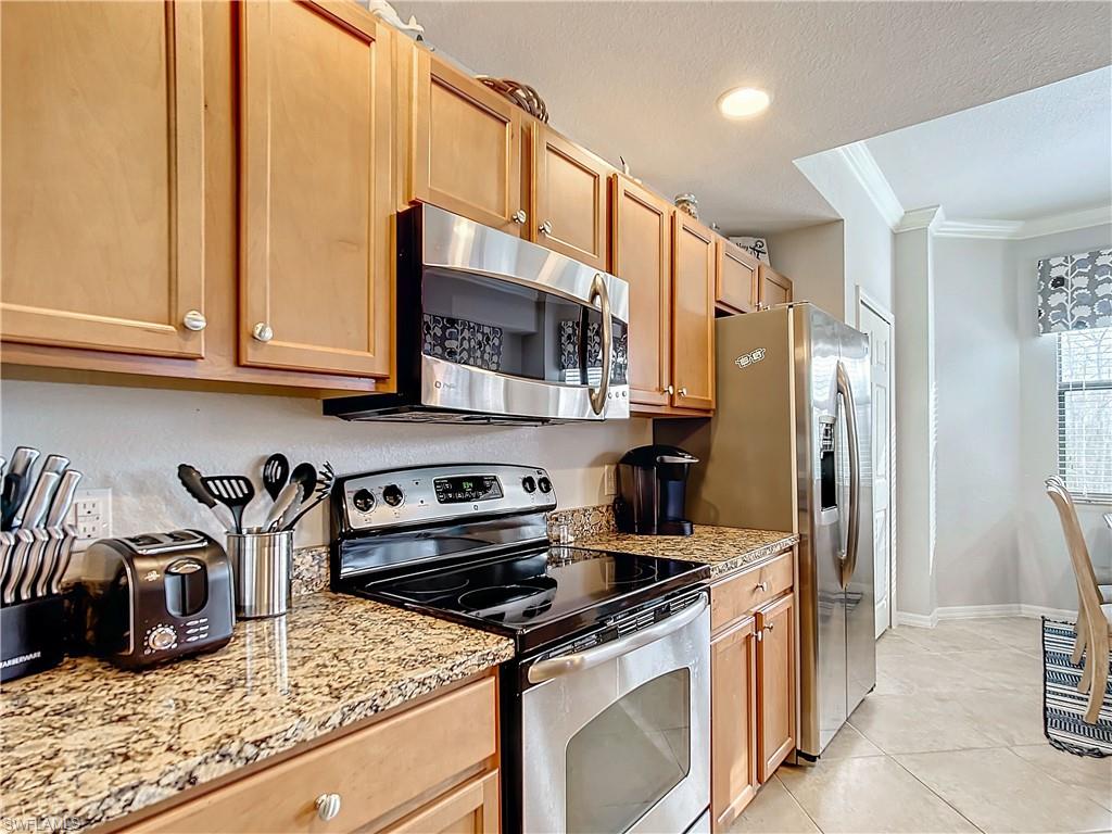 9715 Acqua Court, Unit 127 Naples, FL 34113 - Photo 13 of 50 a kitchen with stainless steel appliances granite countertop a stove a refrigerator and a sink
