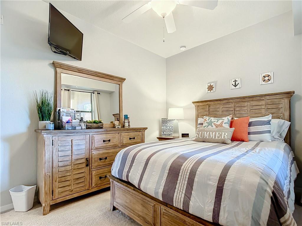 9715 Acqua Court, Unit 127 Naples, FL 34113 - Photo 36 of 50 a bedroom with a large bed and a flat tv screen on dresser