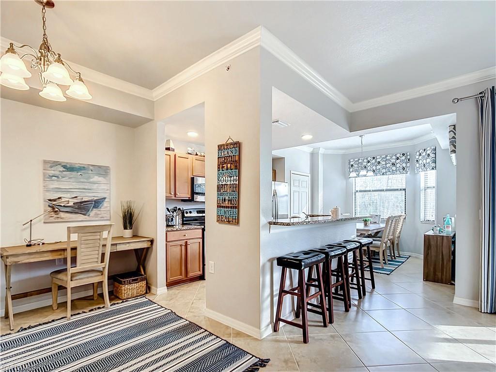 9715 Acqua Court, Unit 127 Naples, FL 34113 - Photo 9 of 50 a kitchen with stainless steel appliances kitchen island granite countertop a table chairs and a refrigerator