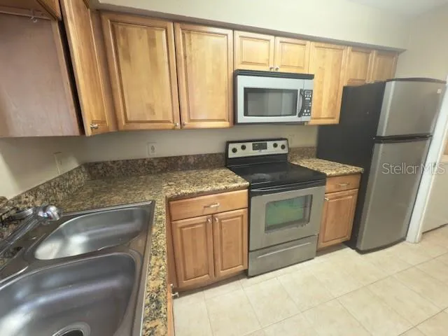 a kitchen with granite countertop a refrigerator stove and sink