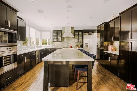 a kitchen with stainless steel appliances kitchen island granite countertop a stove a sink dishwasher and a refrigerator with wooden floor