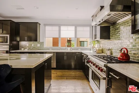 a kitchen with stainless steel appliances granite countertop a stove a sink and a microwave