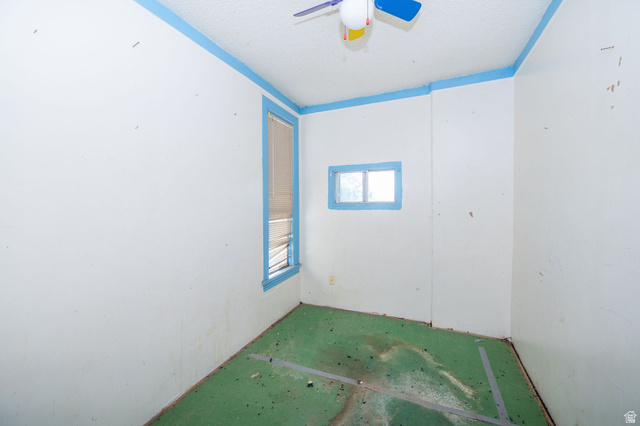1256 24th Street Ogden, UT 84401 - Photo 20 of 34 Room featuring a ceiling fan, two windows with blue trim, and light-colored walls