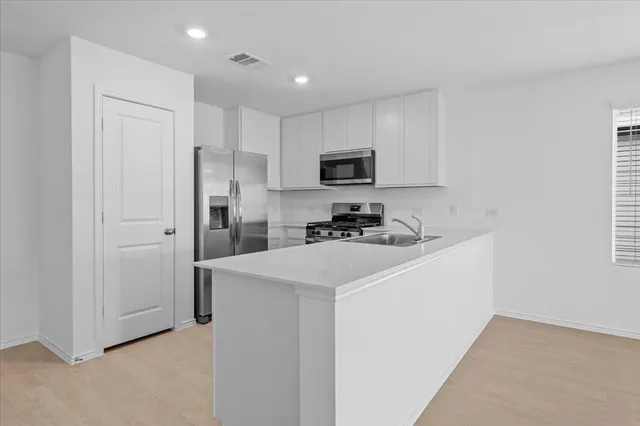 a kitchen with stainless steel appliances kitchen island granite countertop a stove a sink and a refrigerator
