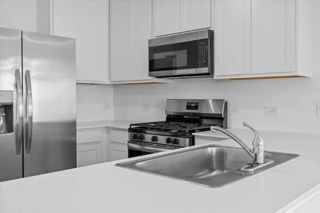 a kitchen with stainless steel appliances a refrigerator sink and microwave