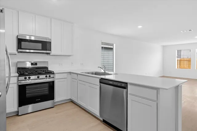 a kitchen with stainless steel appliances granite countertop a refrigerator a microwave a sink and white cabinets