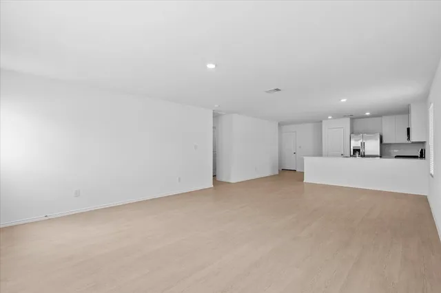 a view of an empty room with a window and wooden floor