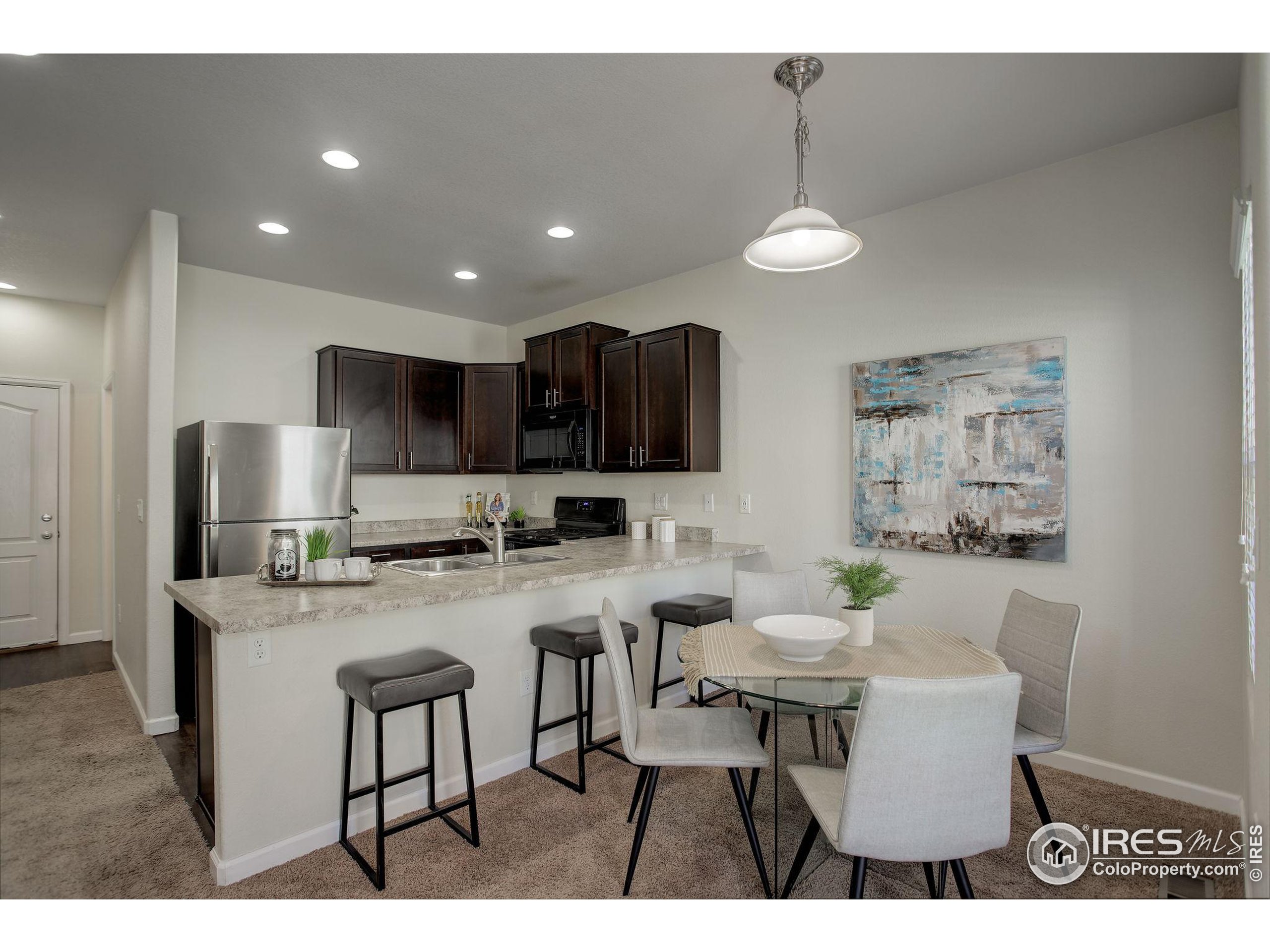 a kitchen with stainless steel appliances granite countertop a sink a stove a refrigerator a dining table and chairs