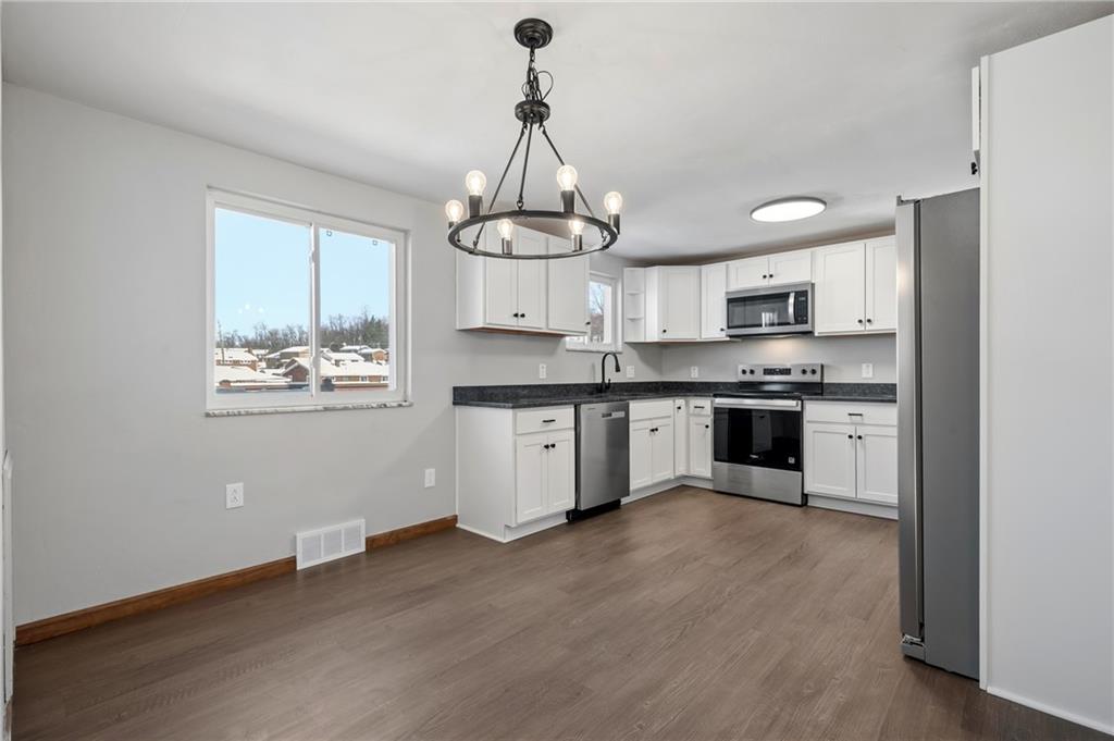 678 Colonial Manor Road Irwin, PA 15642 - Photo 7 of 30 a kitchen with stainless steel appliances granite countertop a stove a sink dishwasher a refrigerator and white cabinets with wooden floor
