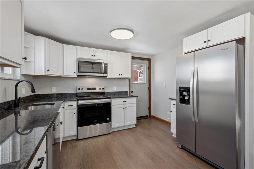 678 Colonial Manor Road Irwin, PA 15642 - Photo 10 of 30 a kitchen with stainless steel appliances granite countertop a stove a sink dishwasher a refrigerator and microwave with wooden floor