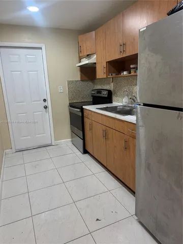 a kitchen with a sink a refrigerator and cabinets