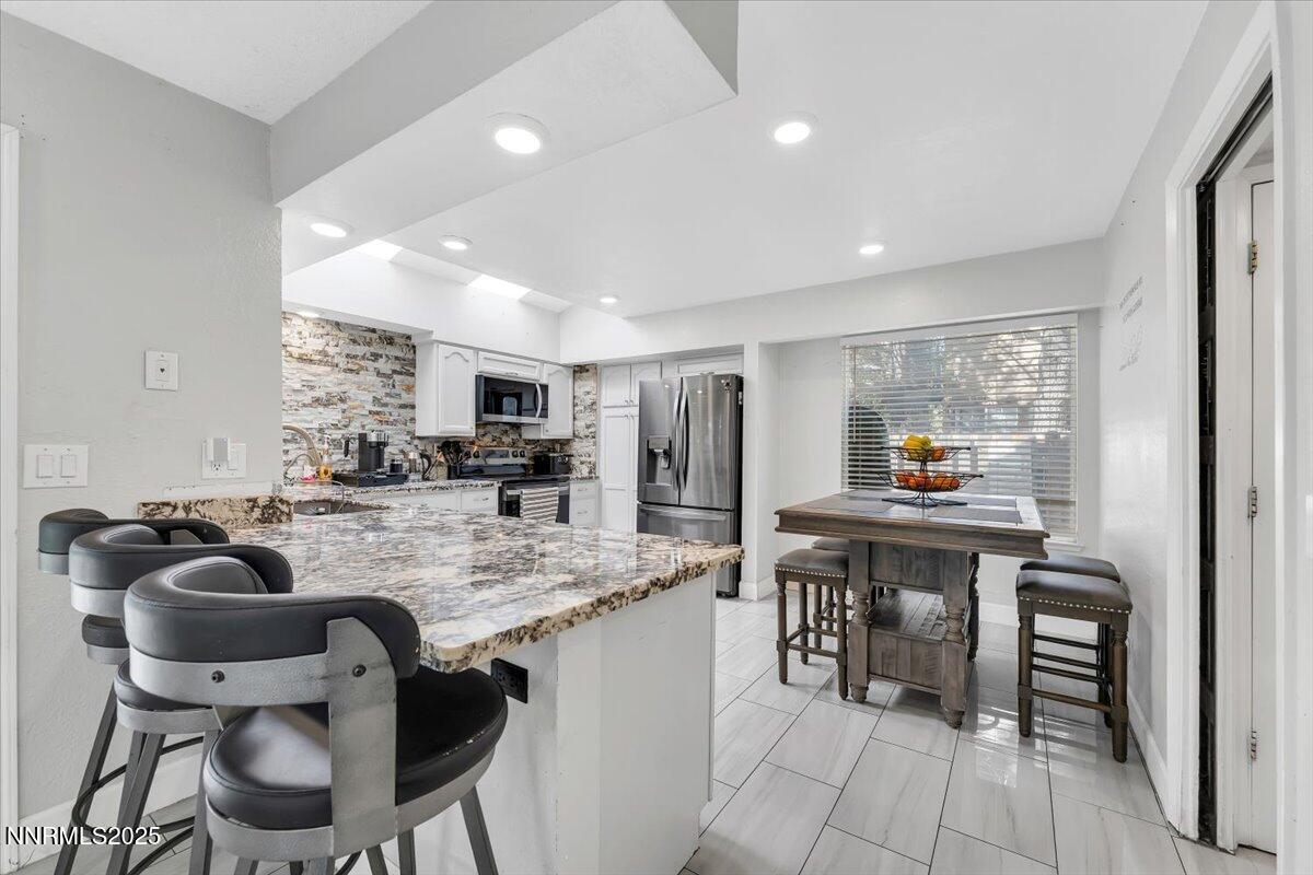 7194 Indigo Court Reno, NV 89506 - Photo 8 of 33 a kitchen with stainless steel appliances granite countertop sink stove and chairs