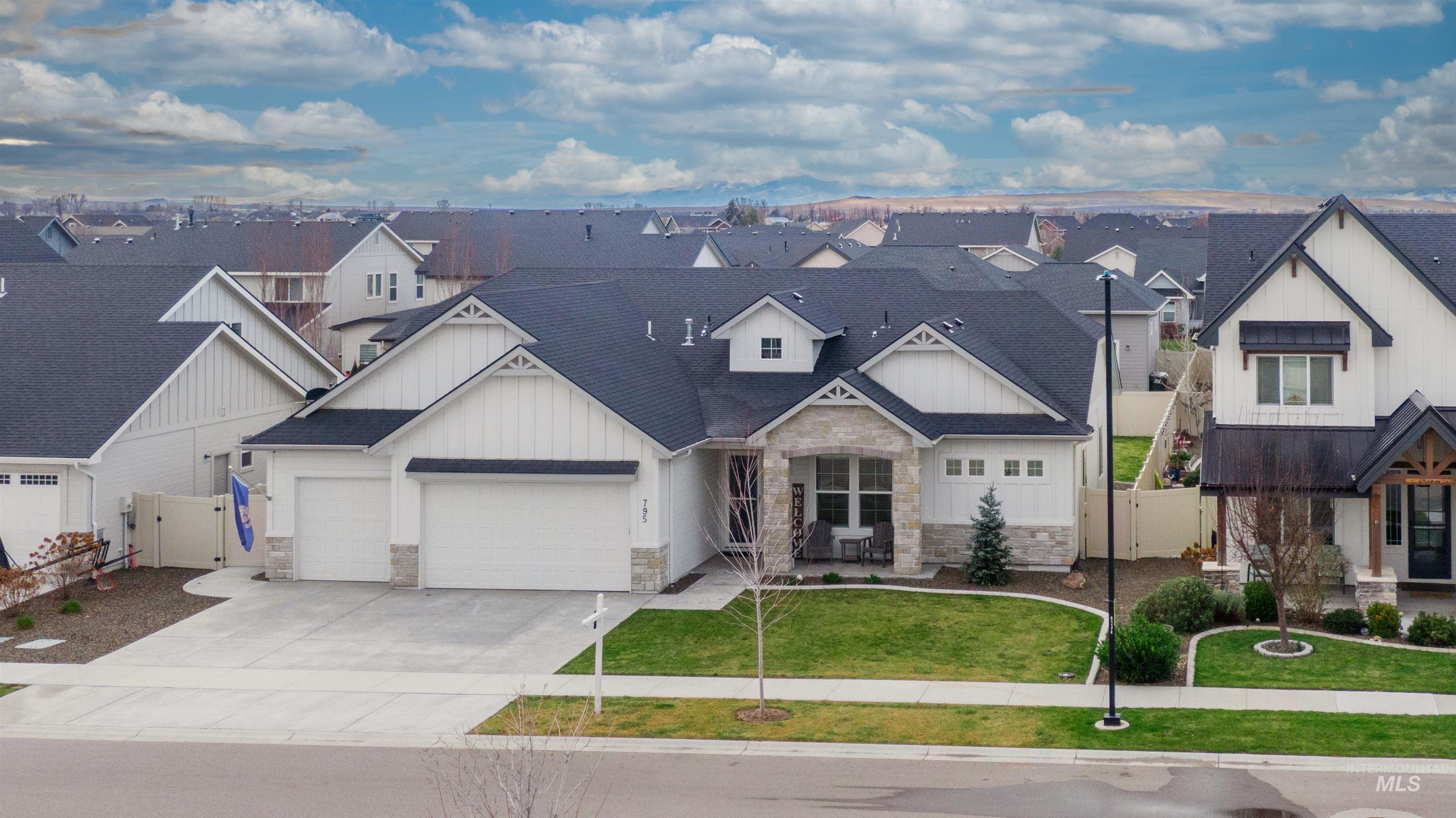 View of front of property featuring stone siding, board and batten siding, driveway, an attached garage, and a residential view