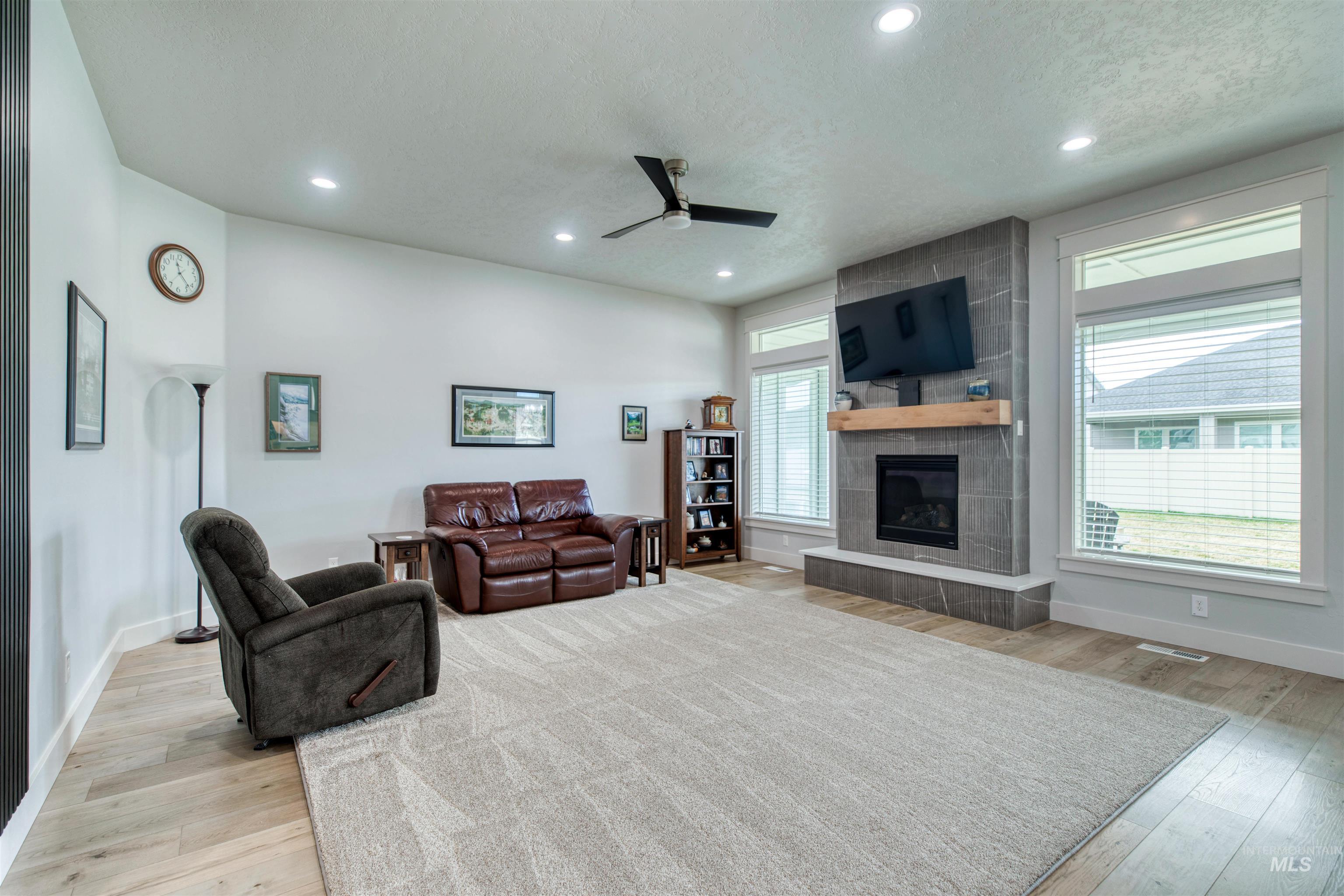 795 East Rio Chico Drive Kuna, ID 83634 - Photo 11 of 34 Living area with a textured ceiling, light wood-type flooring, ceiling fan, a tiled fireplace, and recessed lighting